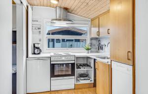 a kitchen with white appliances and wooden cabinets at Hytteby – Hanstholm Camping – Thy Feriepark in Hanstholm