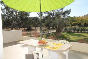 a table and chairs with a green umbrella at Résidence Isola Hotel in Borgo