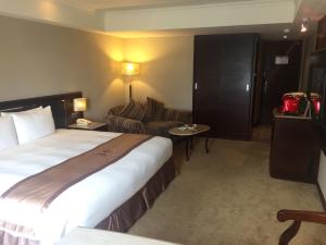 a hotel room with a large bed and a couch at Taichung Charming City Hotel in Taichung