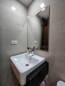 a bathroom with a white sink and a mirror at Casa Antonio at Viceroy McKinley Hill in Manila