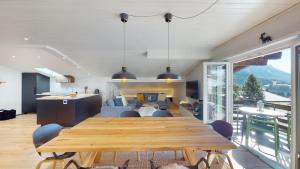 comedor y sala de estar con mesa de madera en Ski in-Ski out Apartment Luscheina-Lenzerheide, en Valbella