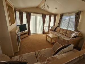 a living room with a couch and a tv at Park Home at Lyons Winkups Holiday Park N.Wales in Kinmel Bay