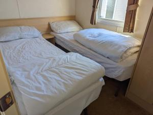 two twin beds in a small room with a window at Park Home at Lyons Winkups Holiday Park N.Wales in Kinmel Bay