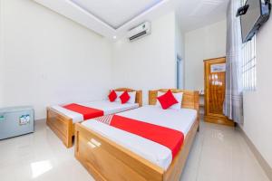 um quarto com 2 camas com lençóis vermelhos e brancos em Hải Phát Hotel em Thôn Trà Long