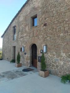 a stone building with a door and two trees in front at Hotel japonès Puigpinós in Lladurs