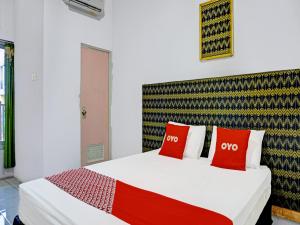 um quarto com uma cama com duas almofadas vermelhas em OYO 91796 Guest House Ghalta Syariah em Karawang