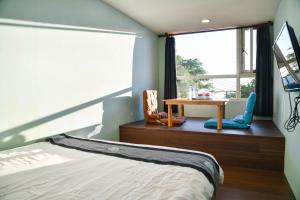 a bedroom with a bed and a table and a window at Way Young House in Jiufen