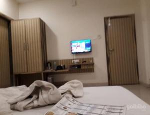 a bedroom with a bed and a tv on a wall at Hotel Gopal, Khargone in Khargon