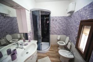 y baño con 2 aseos, lavamanos y ducha. en Affittacamere Oasi di Padru B&B, en Magomadas