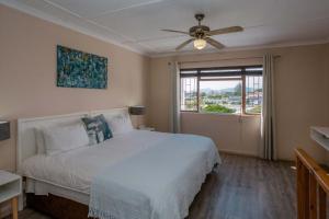 a bedroom with a bed with a ceiling fan and a window at Saxon Lodge in Gansbaai