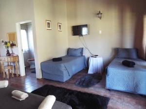 a living room with two beds and a tv at Aloes Country Inn in Waterval Boven