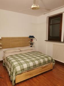 um quarto com uma cama com um cobertor xadrez e uma janela em Luminoso e accogliente appartamento a San Donato em San Donato Milanese