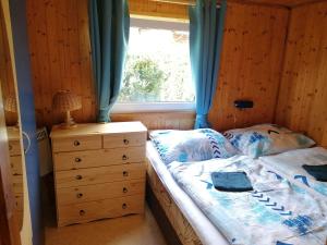 a bedroom with a bed and a dresser and a window at Chata Slapy - Ždáň in Slapy