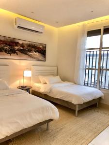 a bedroom with two beds and a large window at Al Majdiah Residence الماجدية ريزدينس شقة عائلية متكاملة in Riyadh