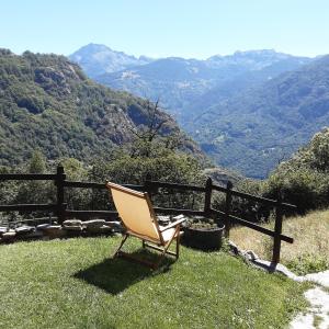 a chair sitting on the grass with a view of mountains at B&B Marcellina in Bard