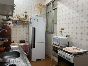 cocina con nevera blanca y microondas en Quarto Camarim, en Río de Janeiro