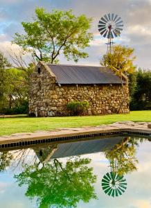 a stone barn with a windmill and a pond at Vergeet-My-Niet in Prince Albert