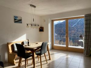 Un comedor con una mesa y un gran ventanal. en Ferienwohnung in Tschlin mit Panoramablick, en Tschlin 