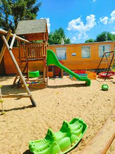 a playground with a green slide in the sand at Chata Slapy - Ždáň in Slapy