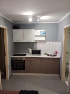 uma cozinha com armários brancos, um fogão e um lavatório em Stadtnah an der Förde 144 em Flensburg