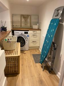 a laundry room with a blue ladder next to a washing machine at Grade Two Listed Cosy Cottage 