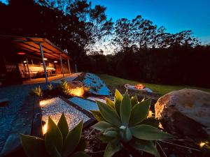 un jardín por la noche con una casa y un cactus en Mesa Bus - Deluxe Byron Hinterland Eco Stay, en Rosebank