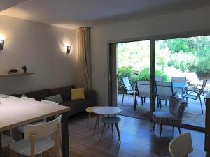 a living room with a couch and a table and chairs at Résidence Cala Sultana N°83 T3 Rez de Jardin 4/6 pers - 50m Plage Santa Giulia in Porto-Vecchio
