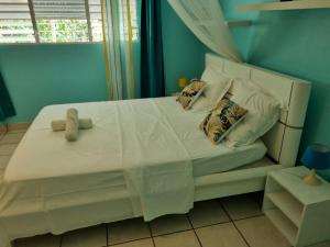 Un dormitorio con una cama blanca con un osito de peluche. en Location tropical, en Sainte-Anne