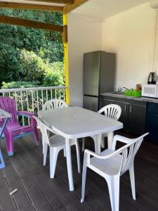 uma mesa branca e cadeiras num deque com uma cozinha em Location tropical em Sainte-Anne