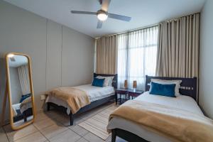 a hotel room with two beds and a mirror at Lovely 3 Bedroom apartment in the heart of Sandton 505 in Johannesburg