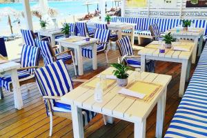 a restaurant with blue and white chairs and tables and the beach at 'Sky and Sea 1' Apartment in Kato Daratso