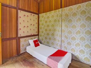 Cama pequeña en habitación con paredes de madera en SPOT ON 91799 Sosonopan Homestay, en Manado