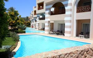 a swimming pool in front of a building at Rehana Royal Beach Resort - Aquapark & Spa - Family & Couples Only in Sharm El Sheikh