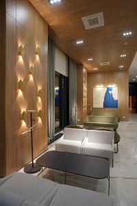 una habitación de hotel con camas blancas y una sala de espera en NEOS HOTEL en Astaná