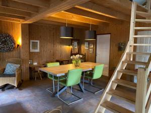 uma sala de jantar com uma mesa de madeira e cadeiras verdes em 't Wettenshuys em Nuenen