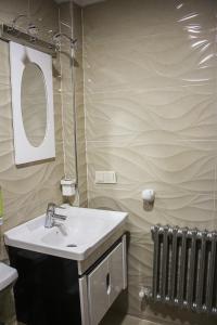La salle de bains est pourvue d'un lavabo, d'un miroir et d'un radiateur. dans l'établissement APPARTEMENT AMIRA iFRANE, à Ifrane