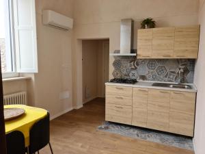 une cuisine avec des placards en bois, une table et une table jaune dans l'établissement Al Palazzotto, à Lucera