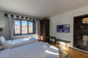 Muktināth的住宿－Lo Mustang Himalayan Resort，酒店客房设有两张床和窗户。