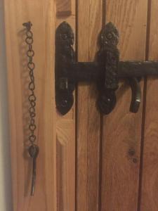 um batedor de porta preto numa porta de madeira com uma corrente em Y Swdio, Ferm Glandwr em Barmouth