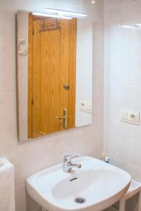 een badkamer met een wastafel en een spiegel met een houten deur bij El Cachalote Feliz in La Rábita