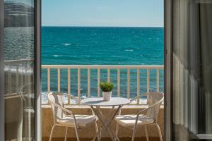 een tafel en stoelen op een balkon met uitzicht op de oceaan bij El Cachalote Feliz in La Rábita