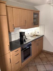 a kitchen with wooden cabinets and a stove top oven at Schöne Ferienwohnung Nähe der Schweizer Grenze in Lauchringen