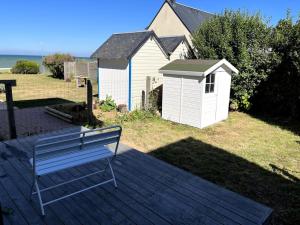 un banco sentado en una terraza junto a una casa en LA CABINE VUE MER en Luc-sur-Mer