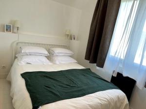 um quarto com uma cama com um cobertor verde em LA CABINE VUE MER em Luc-sur-Mer