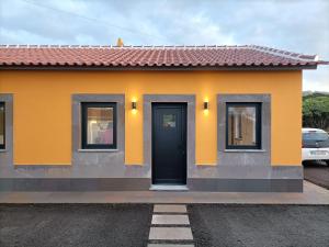 a yellow house with a black door and windows at Casa da Vinha Escondida AL in Biscoitos