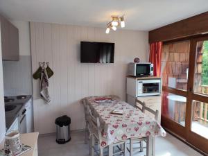 a small kitchen with a table and a tv at Coquet Studio de 4 personnes aux Carroz - Balcon et Wifi in Les Carroz d'Araches