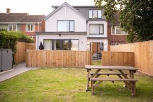 een houten picknicktafel in een tuin met een hek bij Panorama House, Modern 3-Bedroom Apartment 3, Oxford in Kidlington