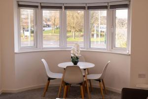 einen Tisch und Stühle in einem Zimmer mit Fenstern in der Unterkunft Panorama House, Modern 3-Bedroom Apartment 3, Oxford in Kidlington + 25 Fotos