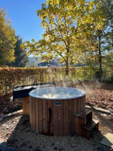 a wooden hot tub in a yard with a tree at Chalet Du Val 53 in Vesin