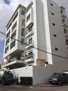 a white building with cars parked in front of it at AYA Mermoz - Superbe appartement dans une résidence récente in Dakar